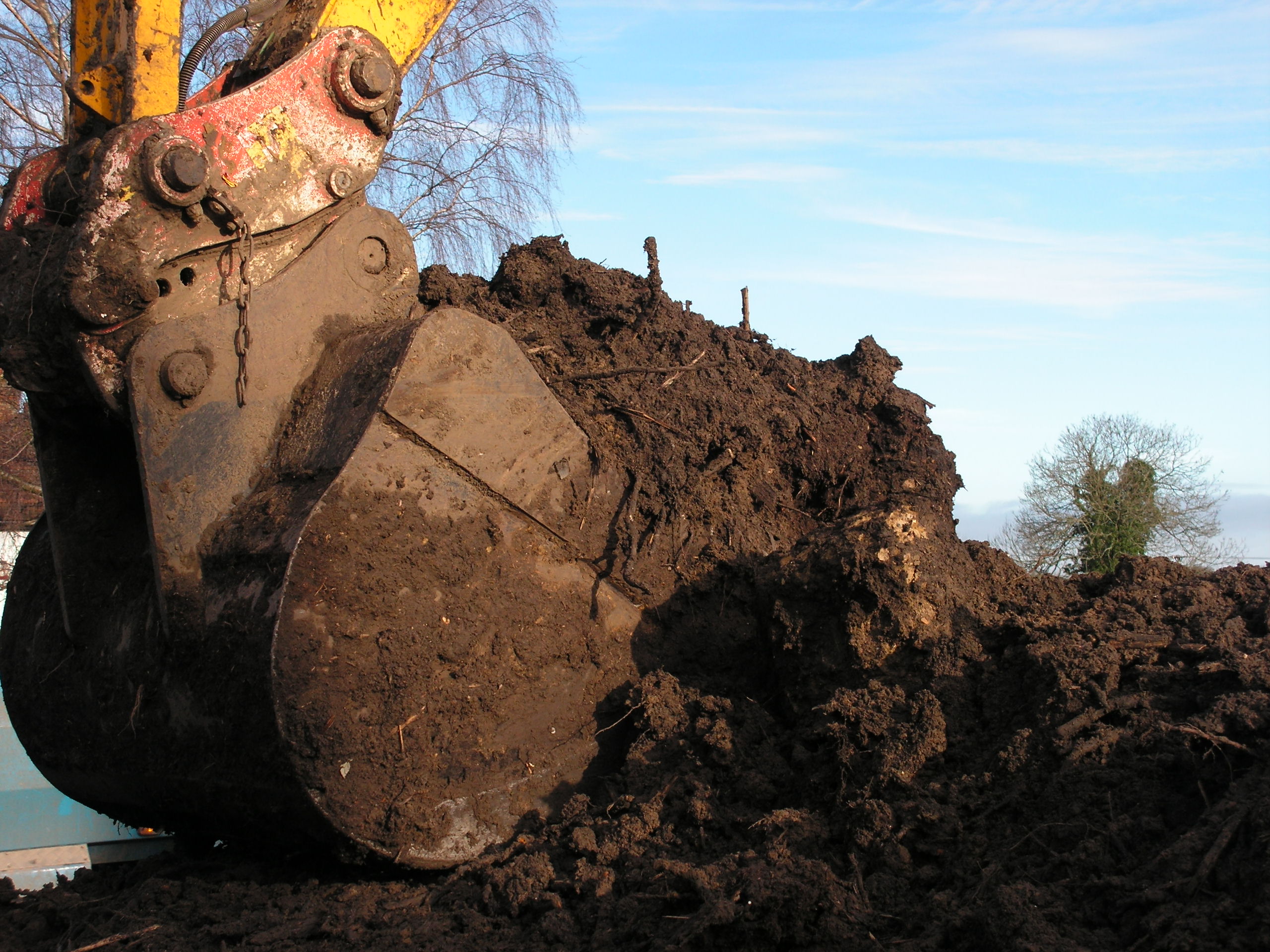 Close up of an excavator foot filled with contaminated ground and soil