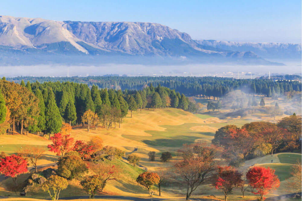 Beautiful pictures of mountains and mist,Pine trees and trees change color Including a golf course in the morning at Aso,Kumamoto prefecture,Japan = Shutterstock