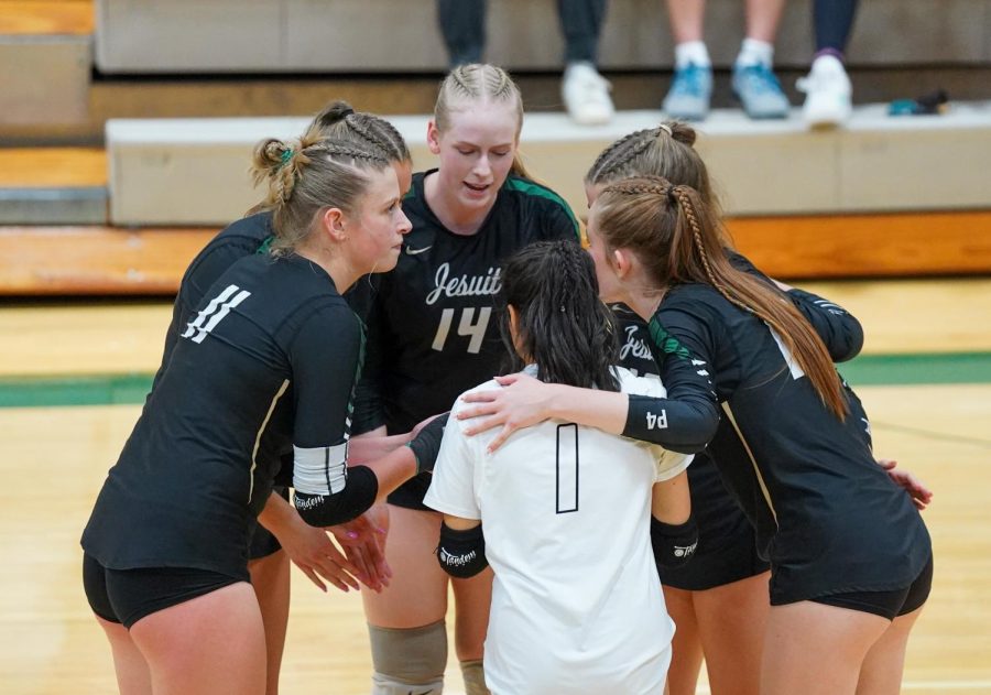 Varsity Women's volleyball team huddle during a match.