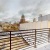 a rooftop patio with a railing and buildings in the background