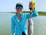 ornella juran wearing blue fishing shirt holding keeper size speckled trout in boga grip