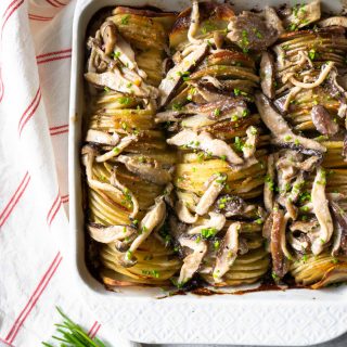 hasselback potato gratin in a white baking dish with chives