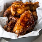 honey old bay wings in a black bowl with white parchment paper