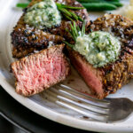 sliced filet mignon on a plate with a fork and green beans