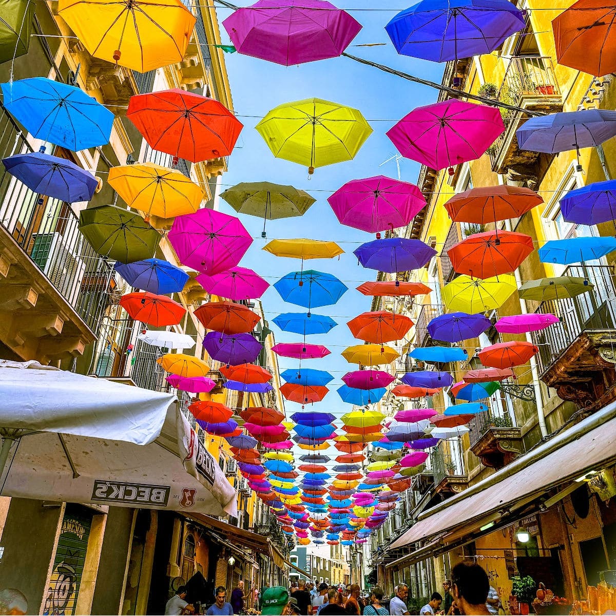 Catania market with colorful umbrellas overhead.