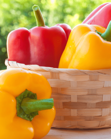 read and yellow bell peppers in wicker basket