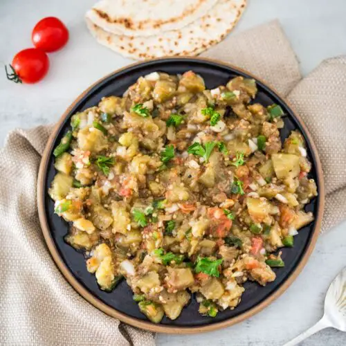 A plate full of vegetables and a tortilla on a table.