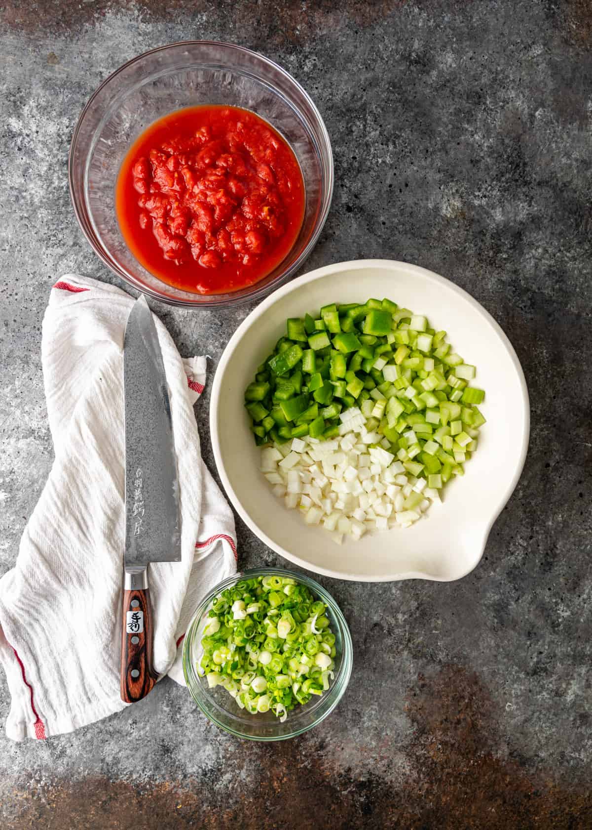 overhead: bowls of tomato sauce and chopped vegetables needed for my jambalaya recipe