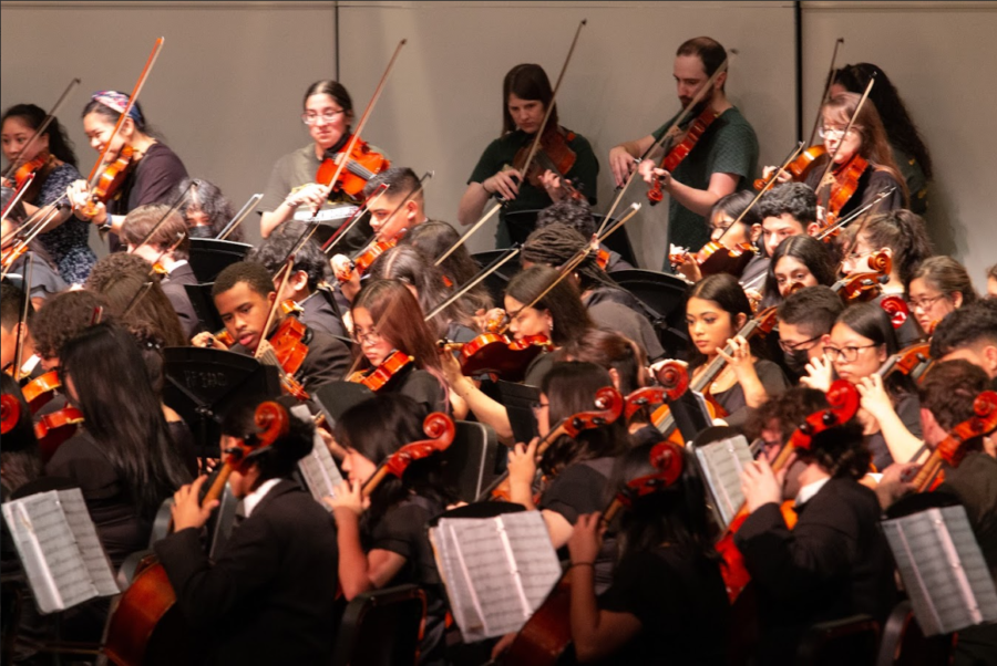 The all-combined orchestra plays along to "Bohemian Rhapsody" by Mercury, arranged by Berry, along with the alumni.