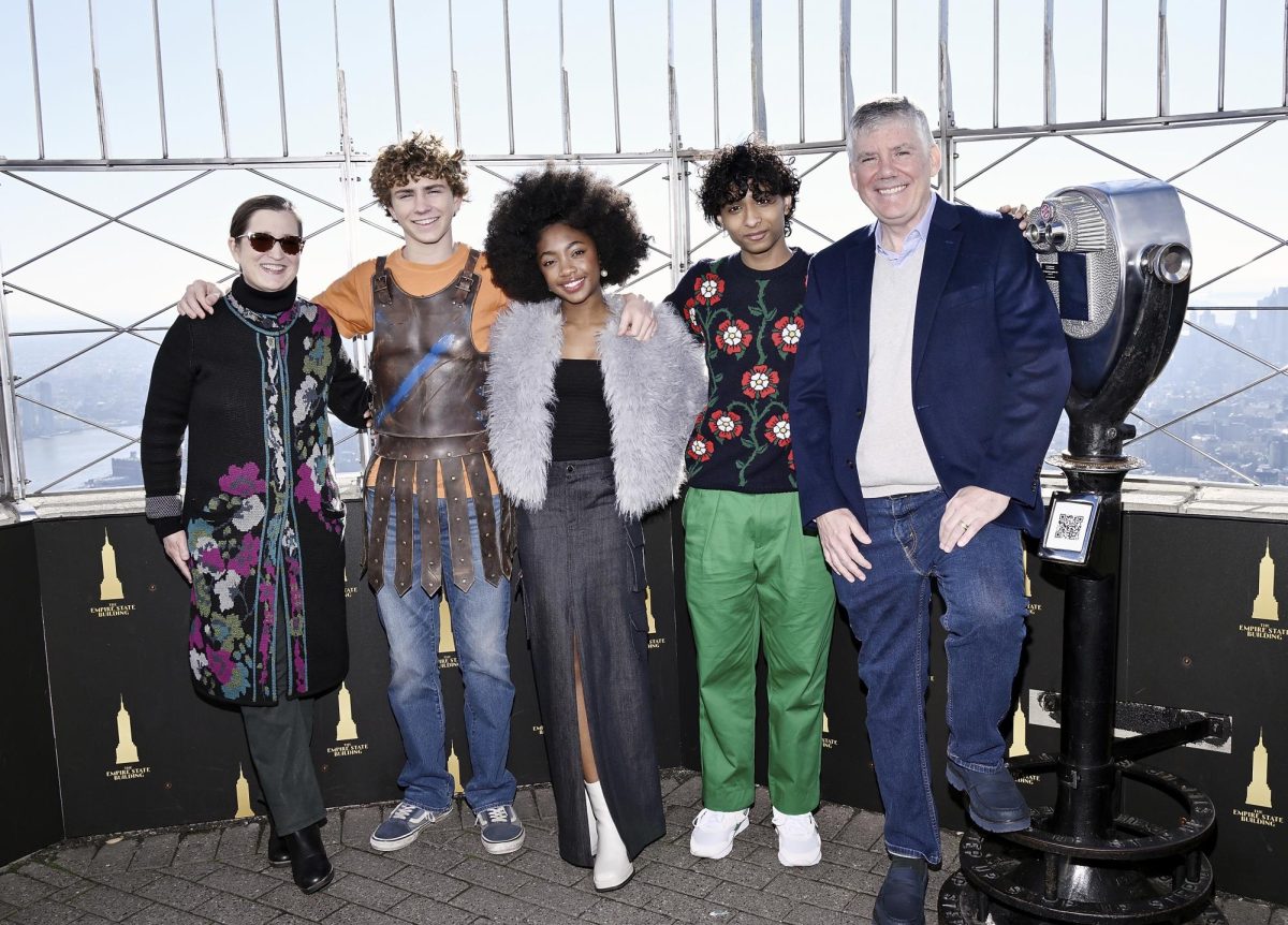 A photo of producer Becky Riordan, Walker Scobell, Leah Sava Jeffries, Aryan Simhadri, and author/contributer Rick Riordan standing in the Empire State Building to film a scene in "Percy Jackson and the Olympians."