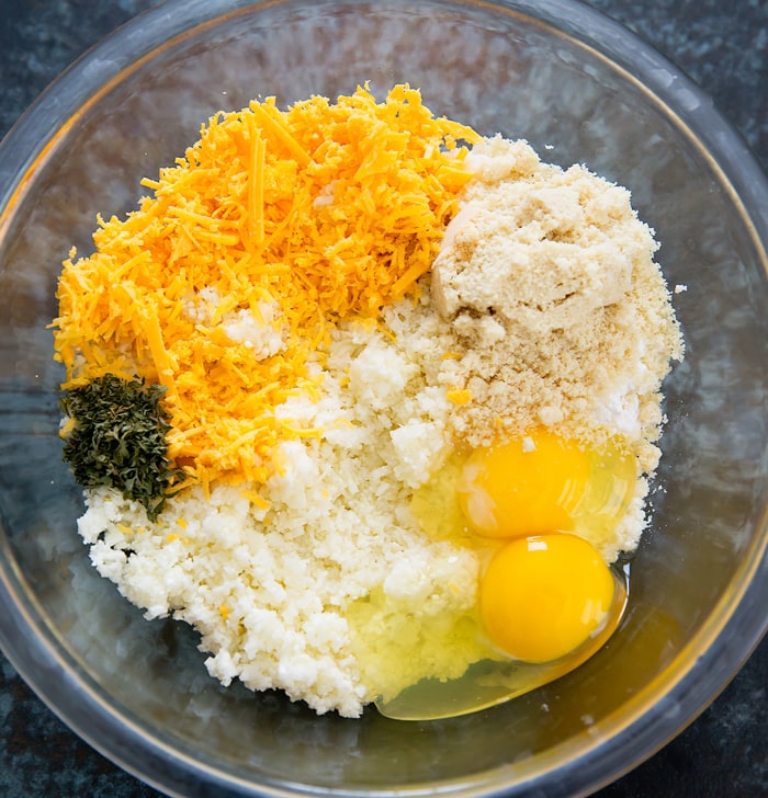 process photo showing the ingredients for cheesy cauliflower muffins in a mixing bowl