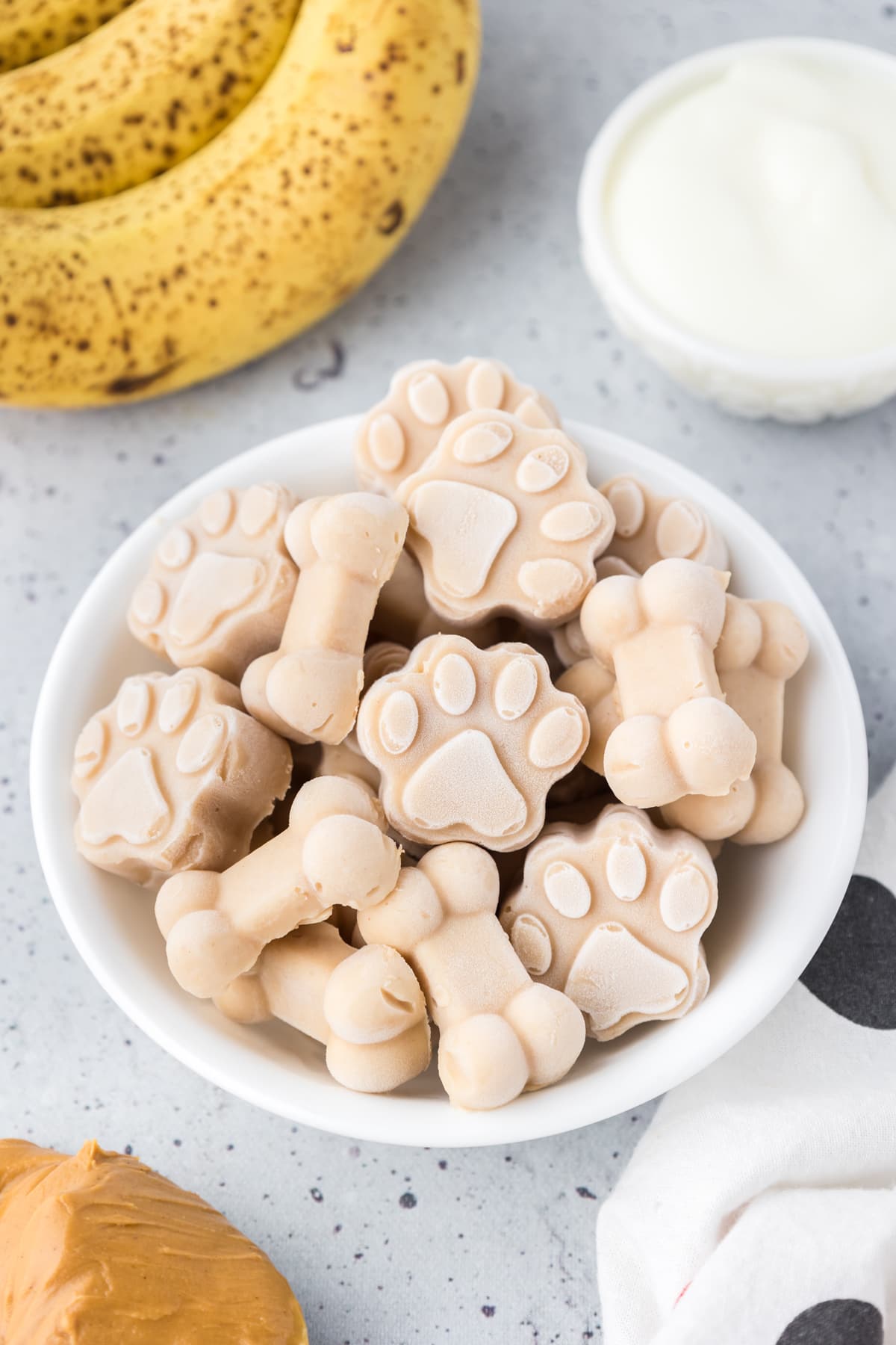 A bowl of dog ice cream shaped like paw prints and bones in a bowl