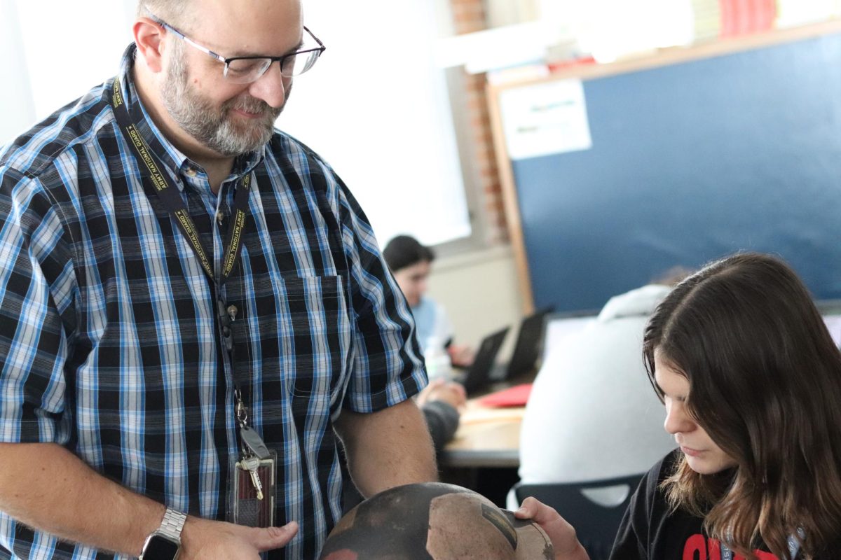 Michael Wright shows junior Elijah Reigle a helmet from World War II. Wright has fun teaching students about military gear in his American Military History class.