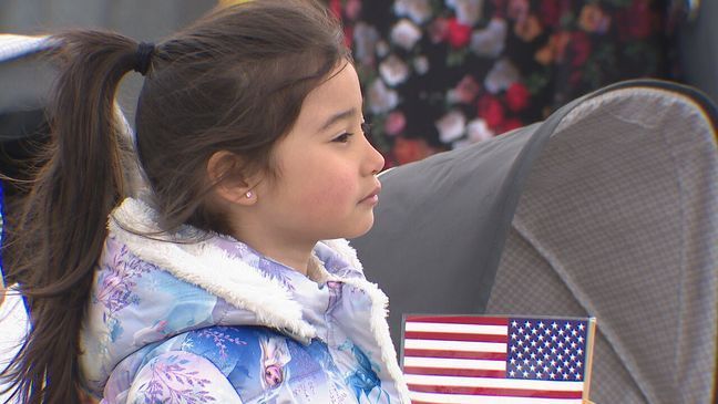  A sailor's daughter holds an American flag, while waiting for the USS KIDD at NAVSTA Everett, May 6, 2024. (KOMO News) 