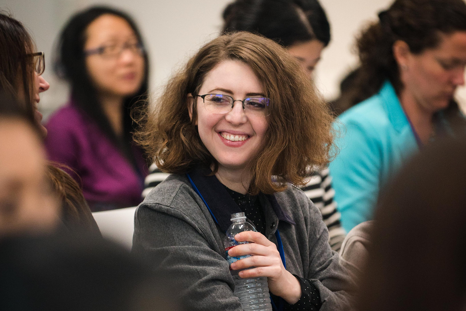 A woman is laughing while holding a water bottle.