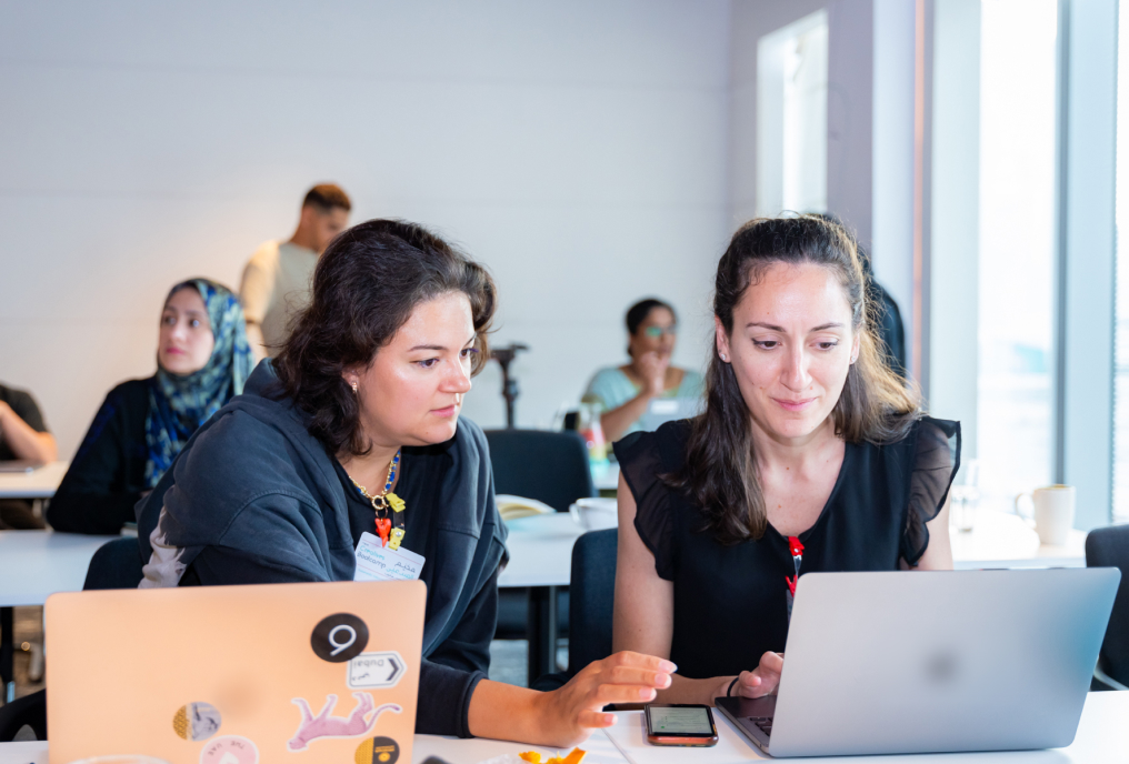 Two women looking into a laptop screen and discussing something.