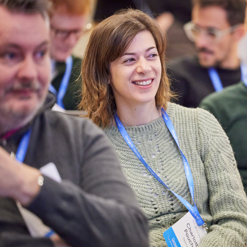 A seated female is observing certain events taking place and is deriving pleasure from said observation.