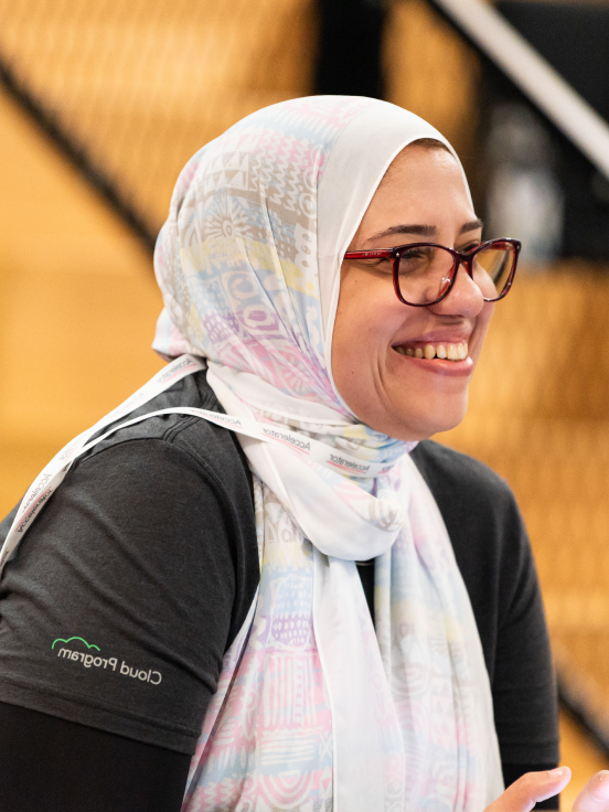 A woman wearing a scarf and a spectacles is smiling.