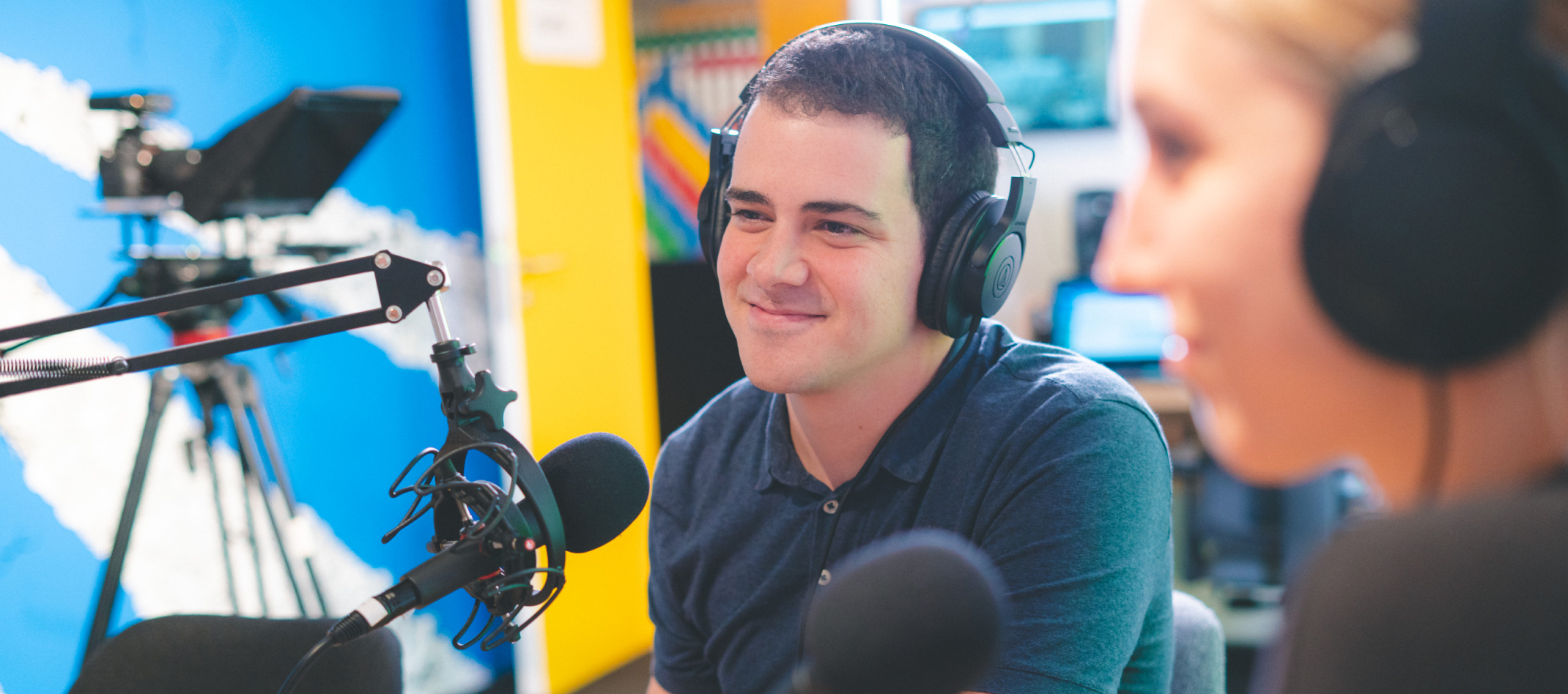 A man sitting in front of a microphone in a recording studio