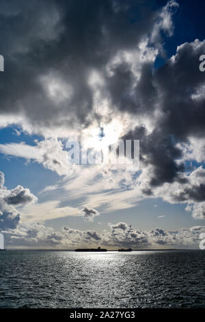 Southend UK 01 October 2019 - Two large cargo ships pass by each other in the Thames estuary off of the Southend coast as they are lit up by sunshine with storm clouds gathering overhead as the tail end of Hurricane Lorenzo heads towards Britain over the next few days  . Credit : Simon Dack / Alamy Live News Stock Photo