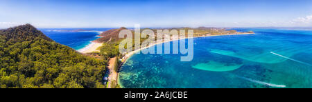 Port Stephens coast Shoal bay town waterfront with Mt Tomaree and Zenith beach in wide aerial panorama over water surface in Australia on a sunny day. Stock Photo