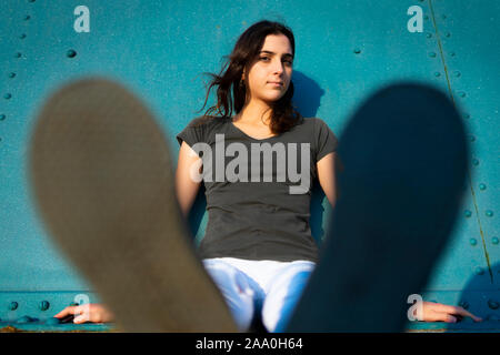 portrait of a girl sit in the street with blue wall Stock Photo