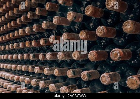 Wine bottles stacked up in old wine cellar close-up background Stock Photo