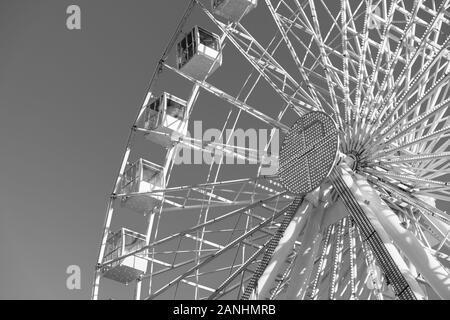 Big ferris wheel is spinning on gray background. People are riding panoramic weel and enjoy city view. Low angle view, copy space and macrophotography Stock Photo