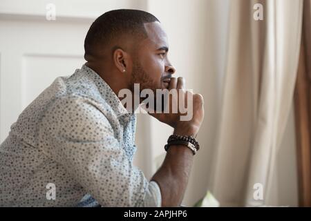 Close up view african guy touches chin thinks looking away Stock Photo