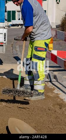 Pipeline mechanic scrubbing sand in construction site in front of a construction vehicle and trailer with shovel in foreground. pipeline mechanic; bro Stock Photo