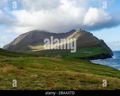 Faroe Islands, Viðoy, Viðareiði. Spectacular view on cliffs and green hills above the village. Blue sky with some while clouds. Stock Photo