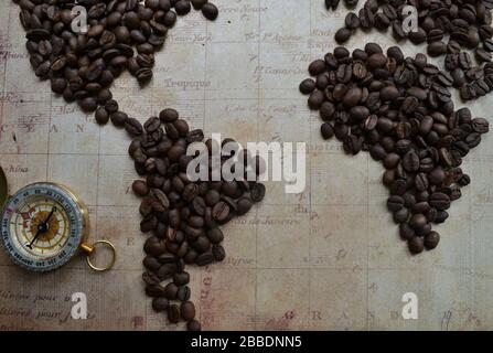 Flat lay world made of coffee beans on the map background with an old brass compass Stock Photo