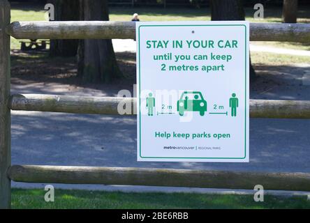 Vancouver, Canada - April 8, 2020: View of sign 'Stay in your car until you can keep 2 metres apart on a parking lot in Capilano River Regional Park Stock Photo