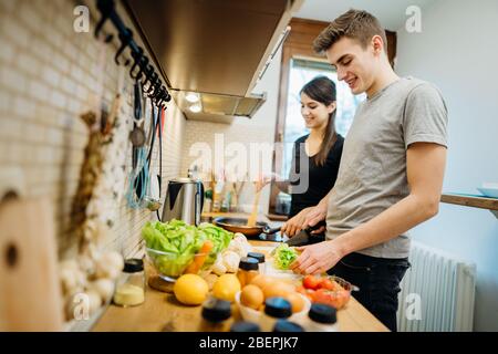 Happy couple enjoying cooking time together at home kitchen.Enjoying simple moments at home.Making vegan dishes.Plant based diet.Having fun while maki Stock Photo