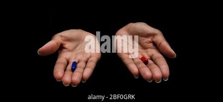 Hands of a black woman offering the red and the blue pills on a black background. Concept of ugly truth vs beautiful lie, reality vs fiction. Stock Photo