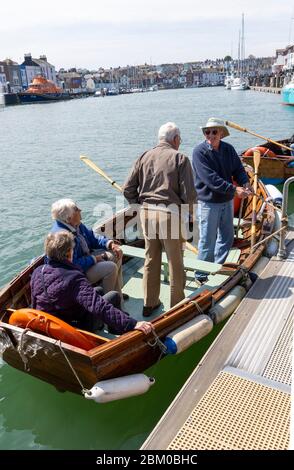 Weymouth, Dorset, England, UK  circa 2014. Elderly people enjoy a trip across Weymouth harbour on a rowing boat ferry. Stock Photo