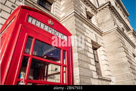 A traditional old red UK telephone box outside one of the many government buildings in Whitehall, London. Stock Photo