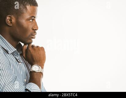 Pensive African American businessman touches his chin with hand with luxury wristwatch. Creative guy generating of idea on white background. Copy Stock Photo