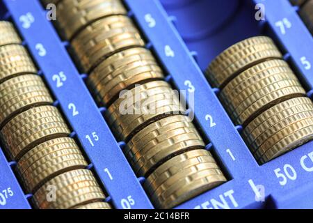 Open cash registrer containing many coins of euros in raw Stock Photo