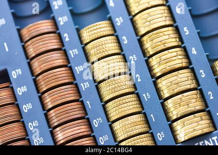 Open cash registrer containing many coins of euros in raw Stock Photo