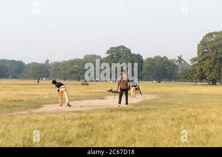 Local Indian boys having fun playing cricket game in Maidan area in the winter sunset evening time near Eden Gardens stadium, city of joy, Kolkata, We Stock Photo