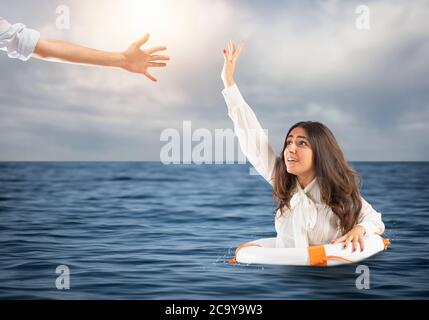 Businesswoman in the ocean with lifebelt receives help Stock Photo