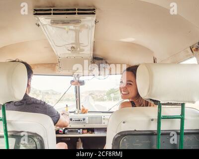 Back view of unrecognizable man driver and young smiling Woman sitting in front in car looking at camera Stock Photo