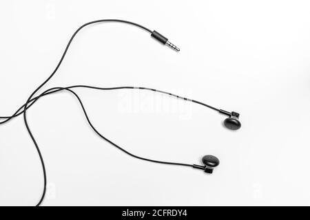 Small black headphones on a light background with tangled long wires Stock Photo