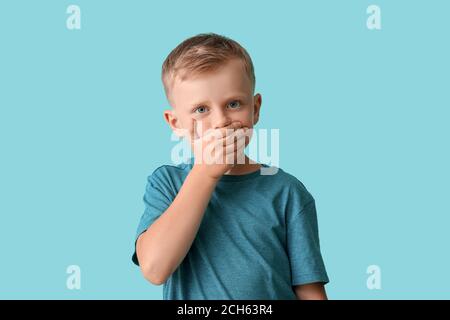 Little boy with autistic disorder covering mouth on color background Stock Photo