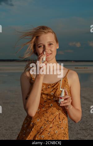 Smiling woman with respiratory spray and throat spray in her hands on the shore of a salt lake, portrait of a woman suffering from respiratory Stock Photo