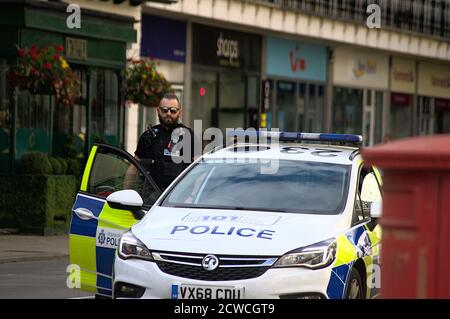 A Warwickshire Police officer standing outside his car in Leamington Spa, wearing sunglasses, next to a postbox on The Parade Stock Photo