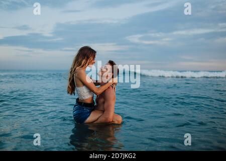 Boyfriend carrying girlfriend while standing in water at beach Stock Photo