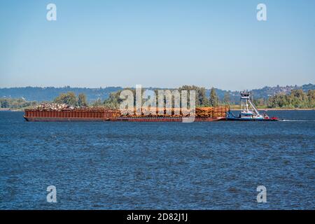 A tugboat pushing a barge carrying logs on the Columbia River Stock Photo