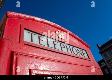 Detail of a red London telephone box. Red phone box lettering and royal crest. In Whitehall, Westminster, London, UK, in bright blue sky autumn day Stock Photo